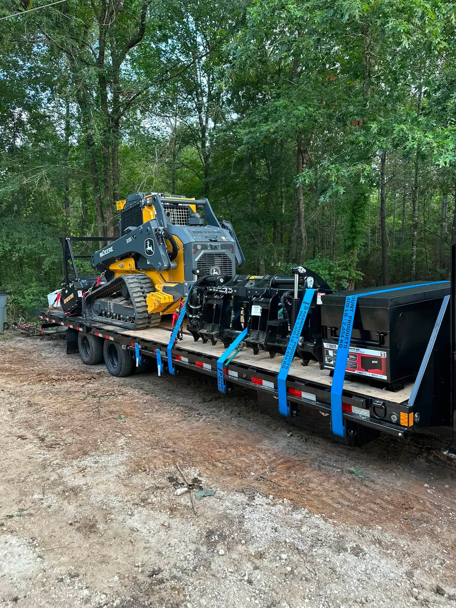 John Deere 335P track loader and attachments loaded on a gooseneck trailer
